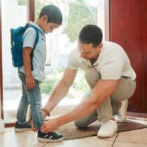父亲和儿子在家里调整鞋子准备上学的照片